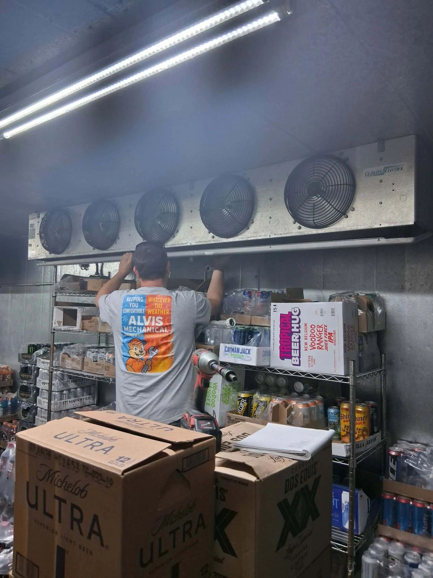 An Alvis Mechanical technician servicing a walk-in cooler evaporator